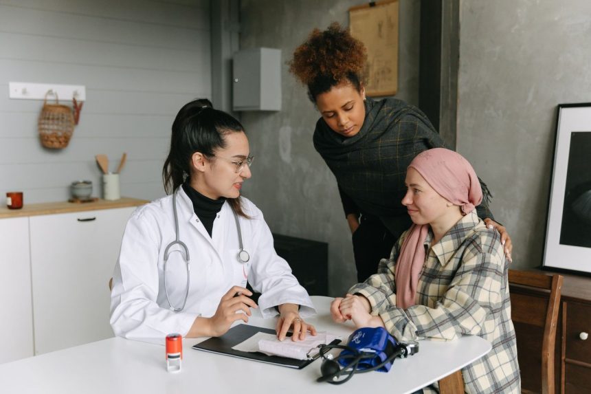 Paciente conversa com um médico e uma pessoa próxima em casa durante um momento de acompanhamento e apoio.