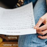 Mão segurando partituras durante uma atividade de estudo e prática musical