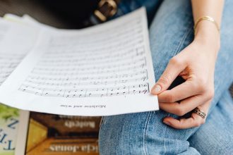 Mão segurando partituras durante uma atividade de estudo e prática musical
