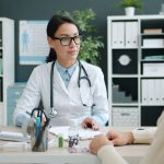 Médico conversa com paciente em uma clínica, discutindo opções de tratamento.