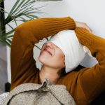 Mulher com curativo na cabeça repousa em ambiente interno durante a recuperação pós-operatória.