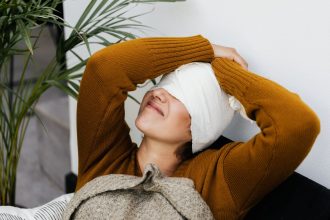 Mulher com curativo na cabeça repousa em ambiente interno durante a recuperação pós-operatória.