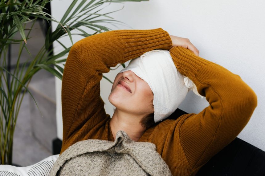 Mulher com curativo na cabeça repousa em ambiente interno durante a recuperação pós-operatória.