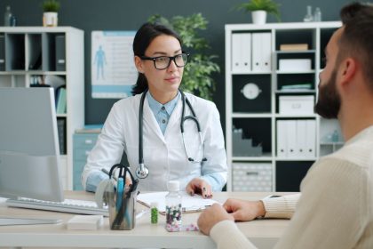 Médico conversa com paciente em uma clínica, discutindo opções de tratamento.